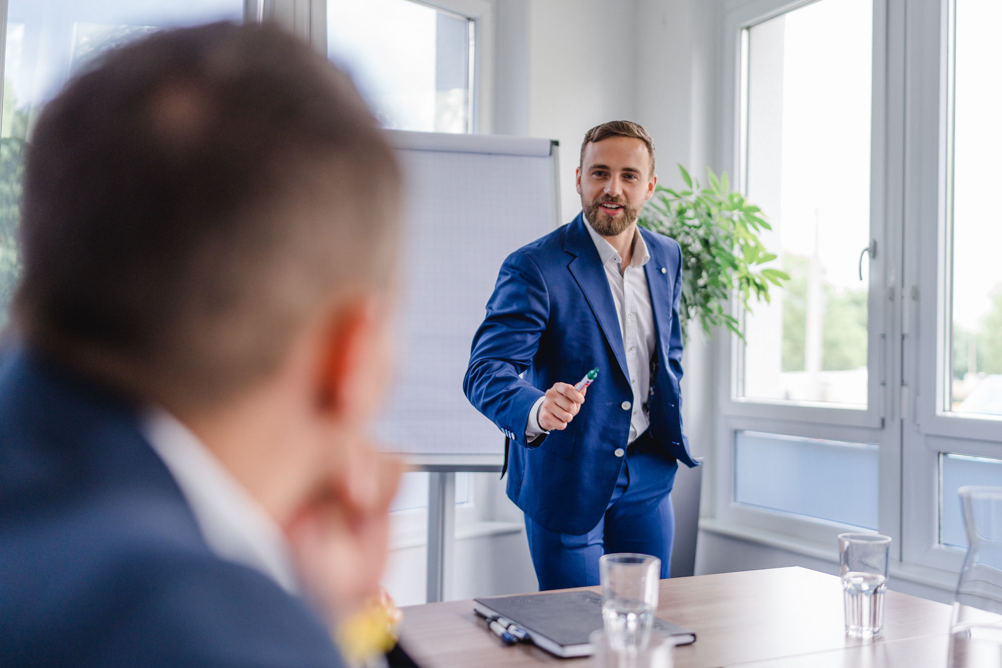 Junger, motivierter Mitarbeiter in Business-Kleidung hält einen bestimmenden und energiegeladenen Vortrag.